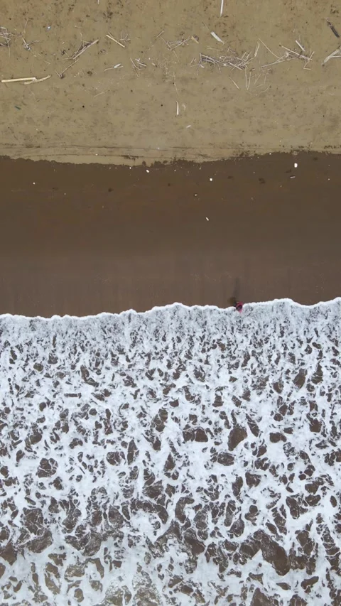 Vertical Drone Shot of Young Man Walking Along Beach at Sunset Stock Footage 326332737