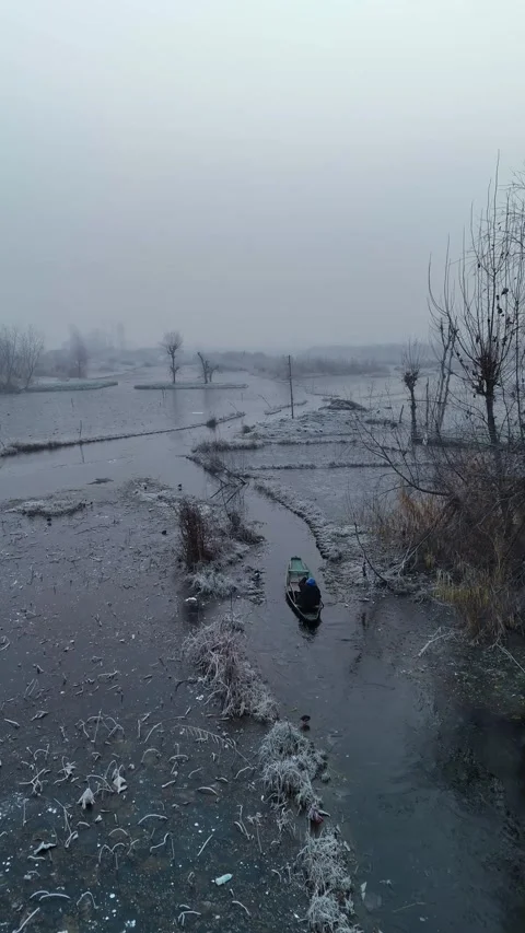 Vertical drone showcasing the hardship of moving boats through Dal Lake’s frozen Stock Footage 311020405