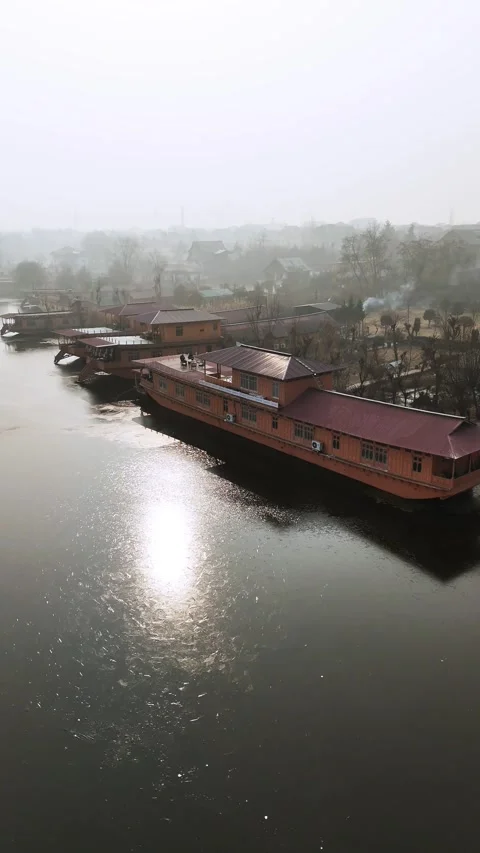 Vertical Drone soaring over a motionless houseboat resting on frozen Nageen Stock Footage 311019359