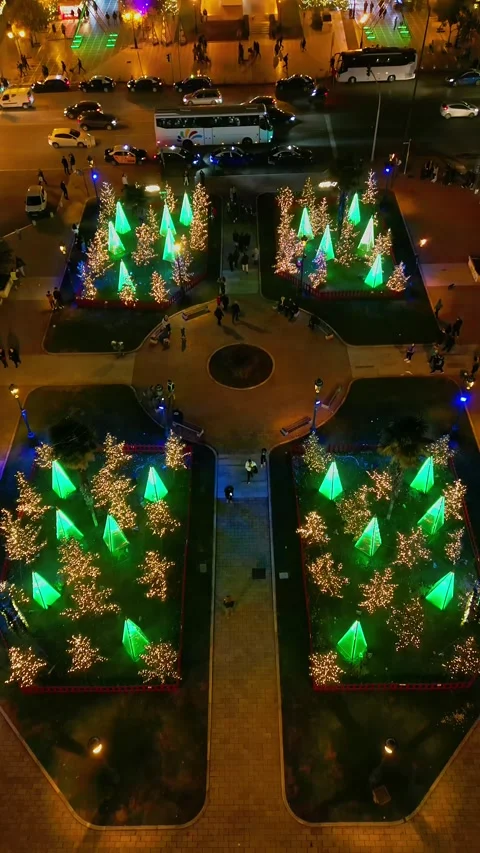 Vertical drone tilt up over glowing Christmas trees and city market Stock Footage 345932354