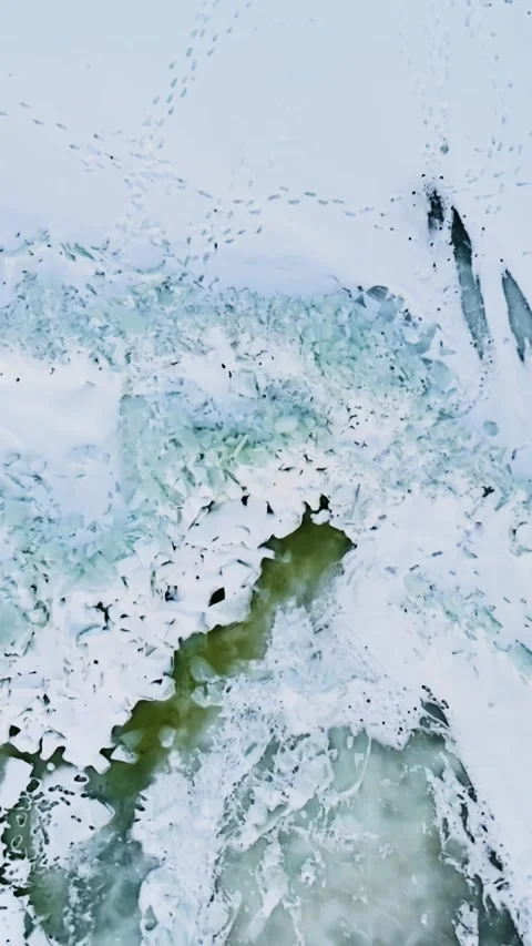 Vertical drone top-down of broken Baltic Sea ice with green meltwater lead and Stock Footage 332088382
