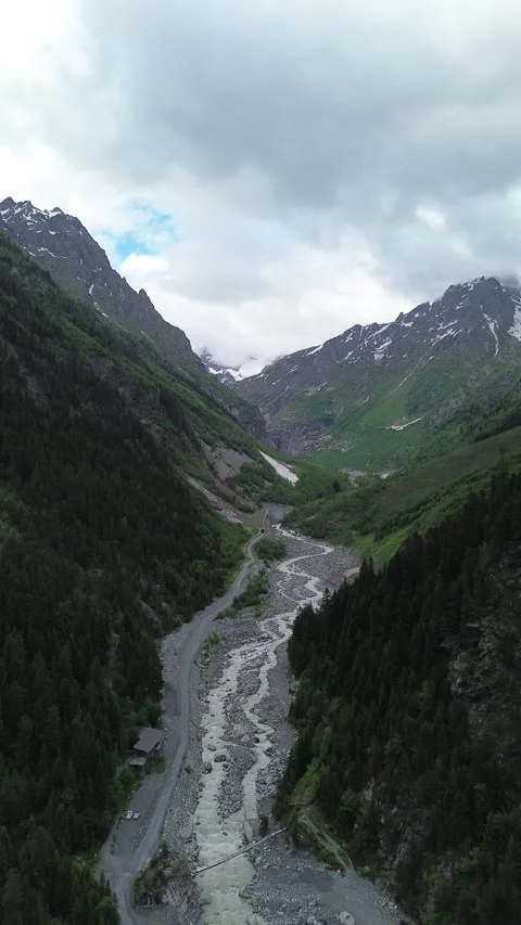 Vertical drone video of the forested Tekhuri river gorge with snow capped pe Video stock 343862570