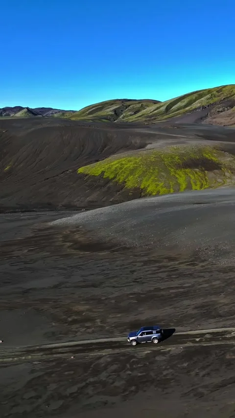 Vertical drone view of a 4x4 driving across Iceland’s black volcanic plain with Vídeos de archivo 331331775