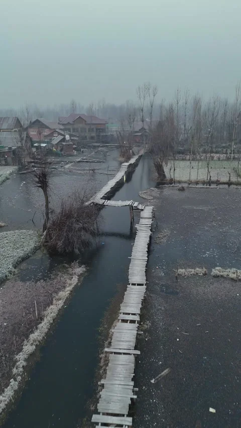 Vertical drone view of desolate, frozen bridges slicing through Dal Lake’s Stock Footage 311020423