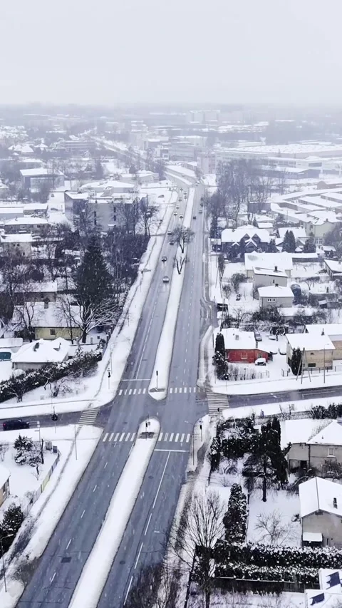 Vertical drone view down a snowy boulevard and crosswalk intersection as light Stock Footage 328910459