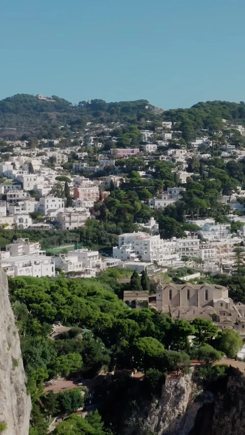 Vertical Drone View Flying Behind a Steep Cliff and Revealing a Beautiful Town Stock Footage 330854243
