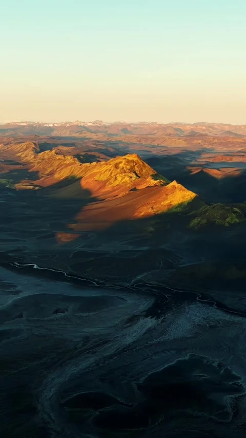 Vertical drone view of Icelandic volcanic highlands at dawn, amber sunlight on Vídeo Stock 331077012