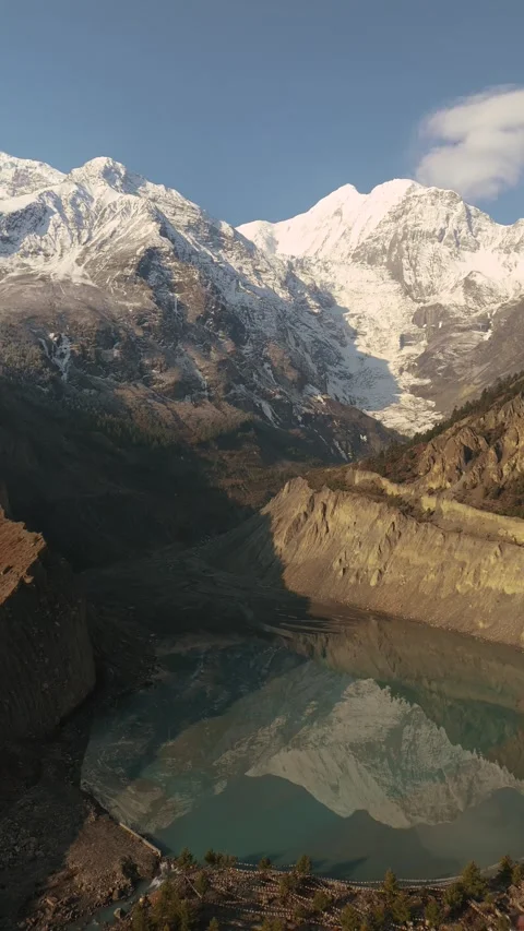 Vertical drone view of Manang’s pristine lake reflecting snow-covered mountains. Stock Footage 311019290