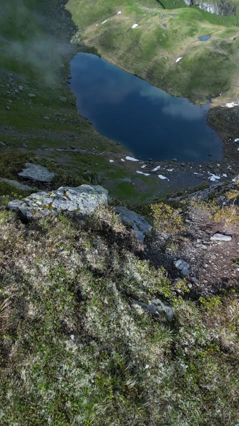Vertical drone view of remote alpine lake in high mountain landscape Video stock 330749596