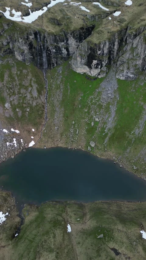 Vertical drone view of remote alpine lake in high mountain landscape Video stock 330749719