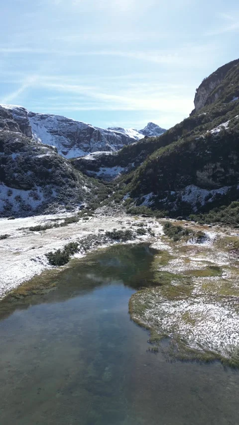 Vertical drone view of remote alpine lake in snow coverd mountain landscape Video stock 330749726