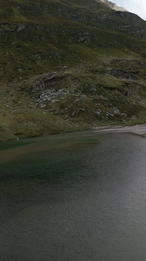 Vertical drone view of remote alpine lake in high mountain landscape Video stock 330749850