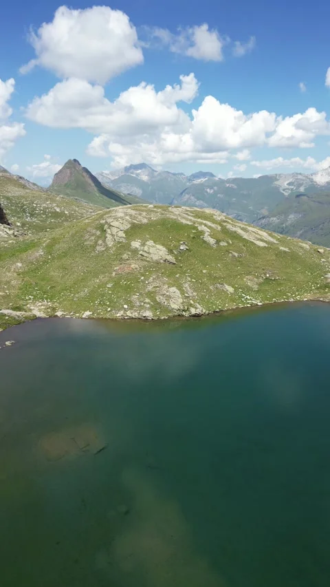 Vertical drone view of remote alpine lake in high mountain landscape Video stock 330749966