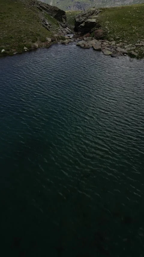 Vertical drone view of remote alpine lake in high mountain landscape Video stock 330750032