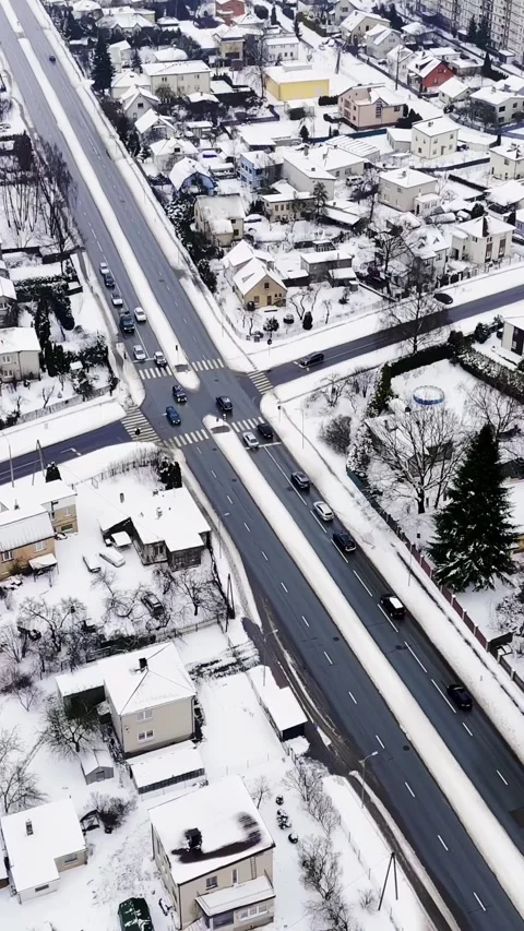 Vertical drone view of a snowy four-way intersection with zebra crosswalks and Stock Footage 328950551
