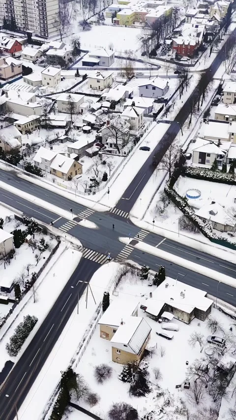 Vertical drone view of a snowy residential crossroads with zebra crossings and 動画素材 328063614