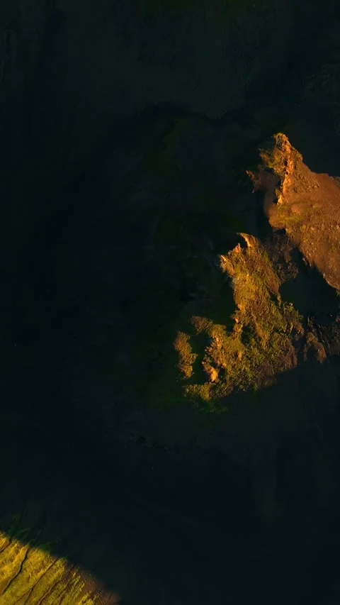 Vertical drone view of sunlit mossy rock outcrops on dark volcanic terrain Stock-Footage 331077019