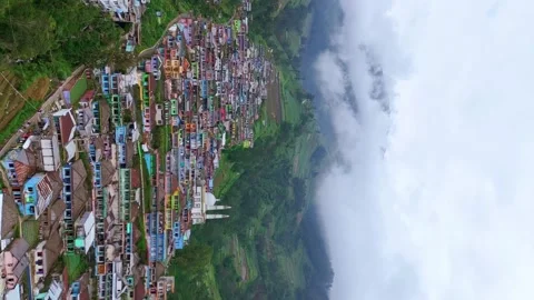 Vertical drone view of vibrant painted houses on steep hillside in cloudy Stock Footage 344432689