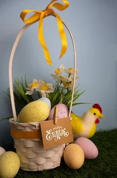 Vertical Easter card with a basket full of pastel colorful eggs, daffodil flo Stock Photos