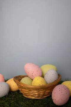 Vertical Easter card with colorful eggs in twigs basket on grass Stock Photos