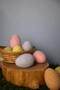 Vertical Easter card featuring pastel colorful eggs in a twigs basket on a wo Stock Photos