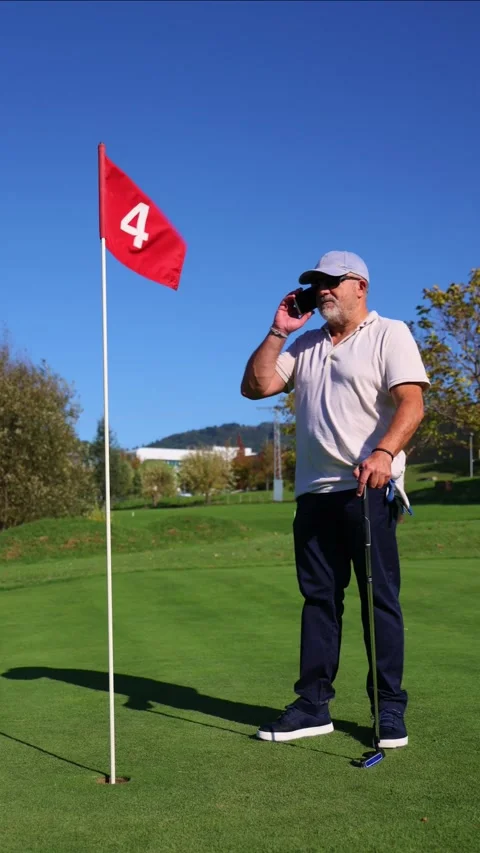 Vertical elderly golfer making a business call near the flag stick during a.. Stock Footage 292017468