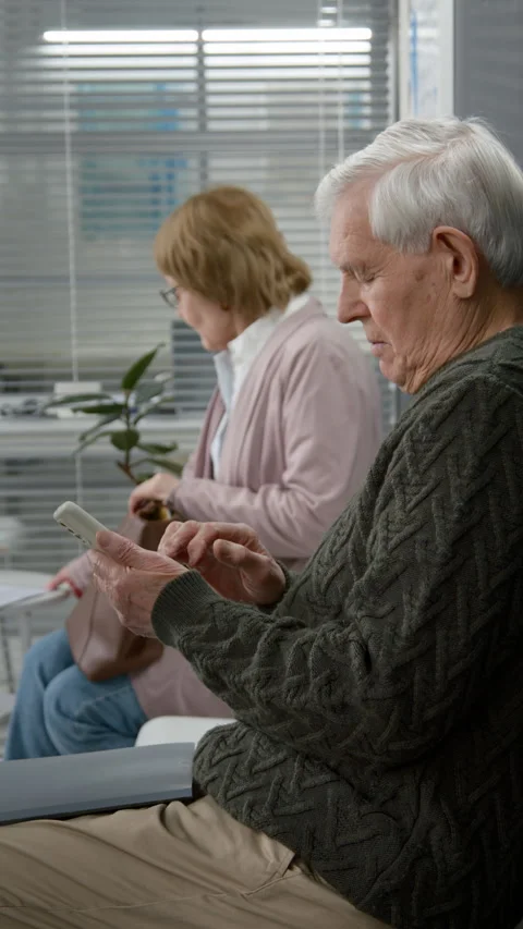 Vertical of Elderly Man Using Phone while Sitting in Waiting Room of Clinic Stock Footage 333206959