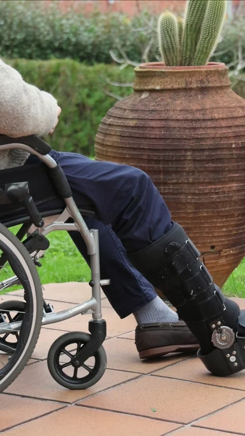 Vertical Elderly man wearing a walking boot sitting in a wheelchair Stock Footage 300172221