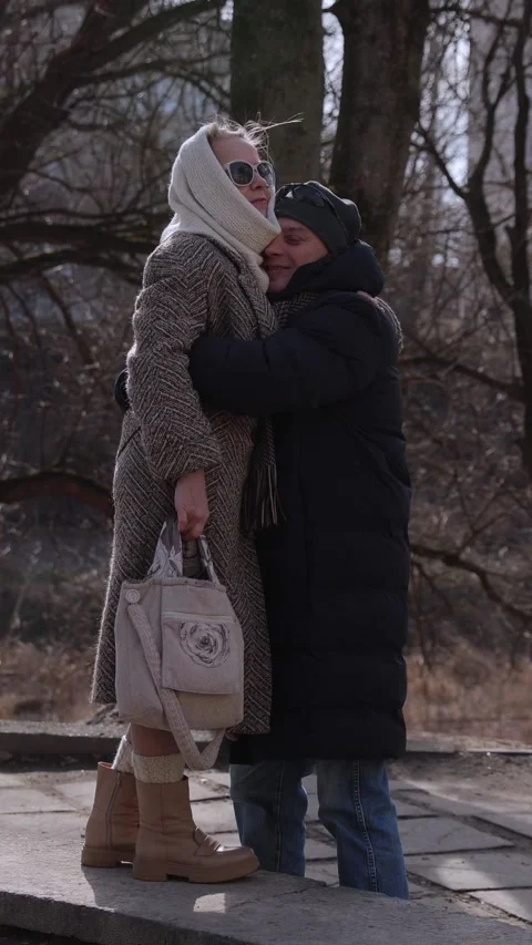 Vertical. Elegant old lady walks along parapet to hug beloved husband in park Stock-Footage 328661994