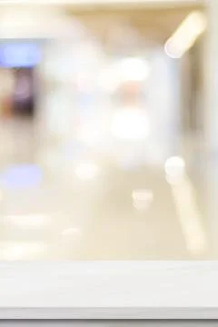 Vertical empty white table top, counter, desk over blur perspective store wit Stock Photos