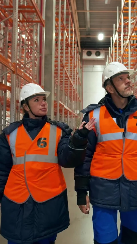 Vertical of Engineers discuss world crisis walking between empty racks Stock Footage 275620638