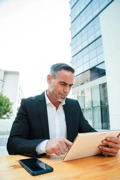 Vertical. Executive businessman using tablet at outdoor cafe successful middle Stock Photos