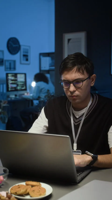 Vertical of Fatigued QA Specialist Testing App on Laptop in Dimly Lit IT Office Video stock 329612232