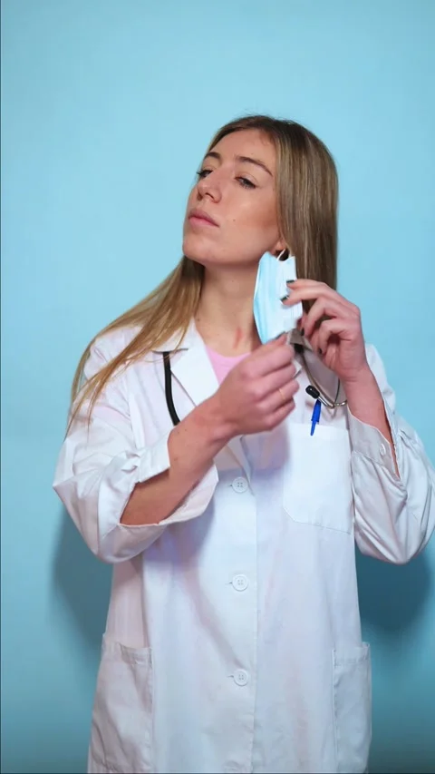 Vertical Female Doctor Removing Protective Mask on Light Blue Background Stock Footage 297675271