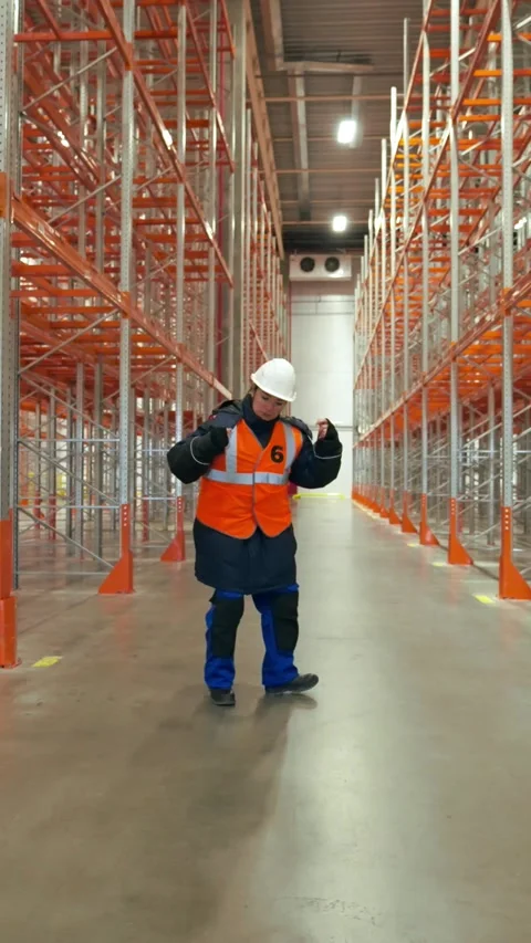 Vertical of Female engineer dances on aisle between empty metal racks Stock Footage 275625025