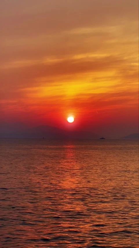 Vertical Fiery Red Sunset Over Calm Sea with Mountain Silhouette on Horizon Stock Footage 331850727