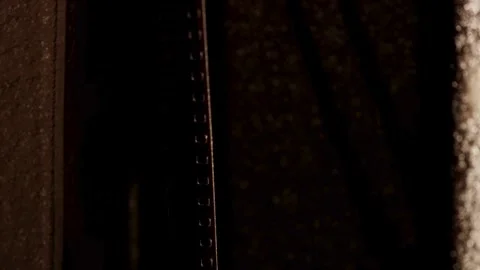 Vertical film strip pulled through old movie projector gate Stock Footage 329746385