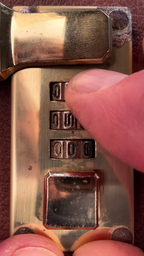 Vertical - Fingers opening the latch of a three number brass combination lock. Stock Footage 281578441