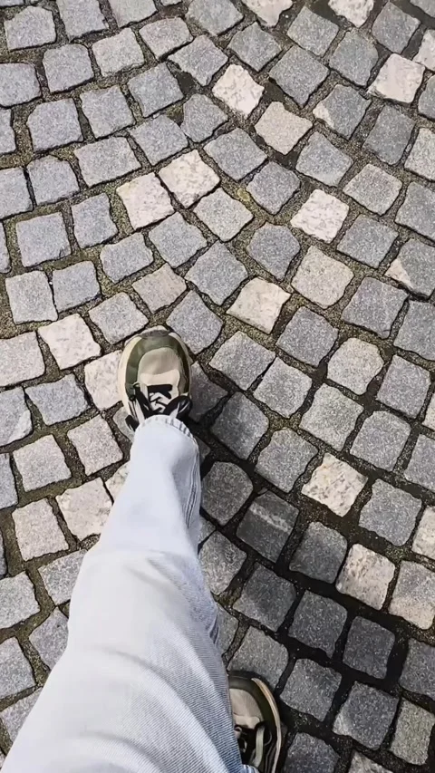 Vertical first-person view of someone walking across patterned cobblestone Stock Footage 344009571