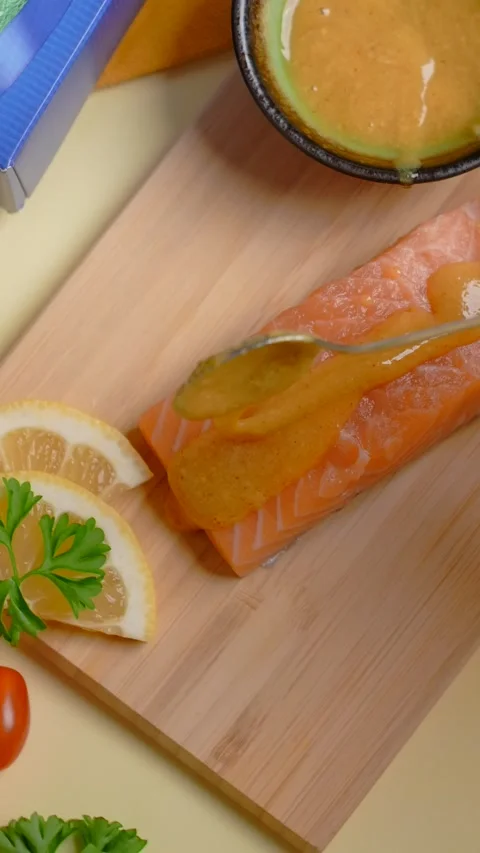 Vertical flat lay: the chef smears a piece of salmon with sauce before baking on Stock Footage 178840753