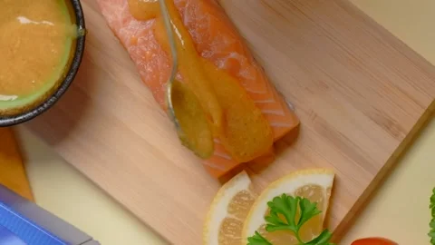Vertical flat lay: the chef smears a piece of salmon with sauce before baking on Video stock 180943654