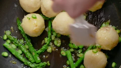 Vertical flat lay food video: the cook fries potato dumplings with asparagus on Stock Footage 181869968