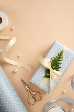 Vertical flat lay of light blue polka dot gift box tied with cream ribbon a.. Stock Photos