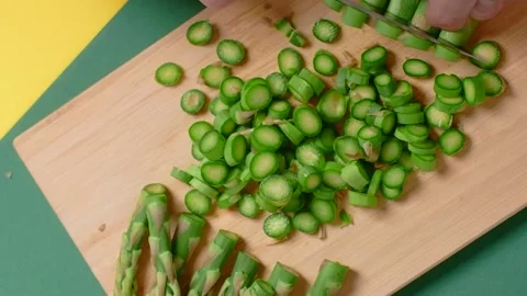 Vertical flat lay video: the cook cuts raw asparagus on the wooden board Stock Footage 180968946