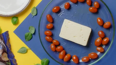 Vertical flat lay video: the cook puts feta cheese to the plae with cherry Stock Footage 181849252