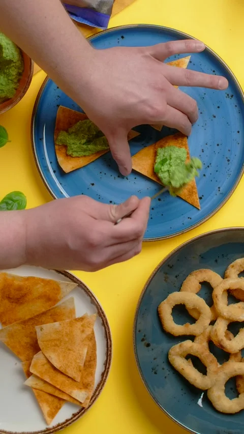 Vertical flat lay video: man makes bachos with pesto and onion rings snack Stock Footage 178905033
