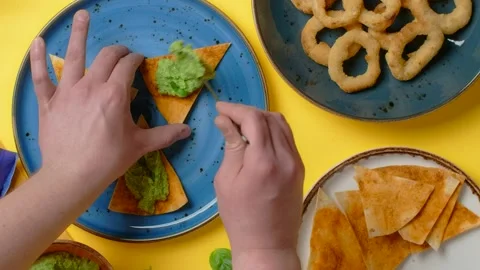 Vertical flat lay video: man makes nachos with pesto and onion rings snack Stock Footage 181109762