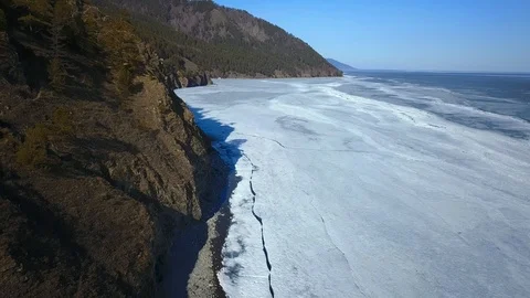 Vertical fly view of frozen surface of Baikal lake coast Stock-Footage 94134179