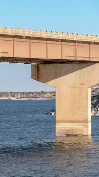 Vertical Focus on a beam bridge supported by abutments over blue lake against Stock Photos