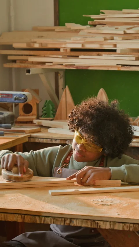 Vertical of Focused Adolescent Kid Sanding Wooden Piece at Carpentry Lesson Stock Footage 334418315